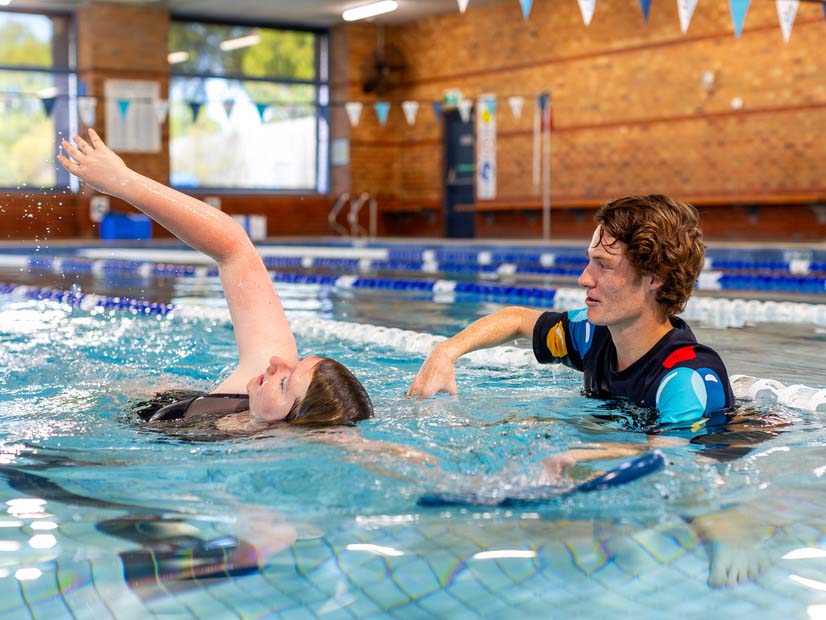 Kingswim instructor helping an adult swimmer improve their stroke technique