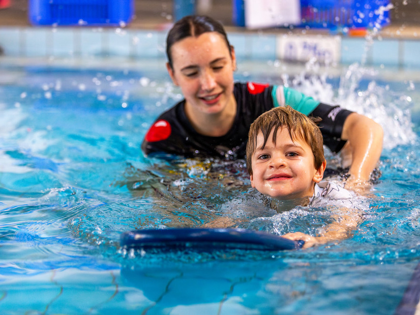 Instructor helping a child learn how to swim