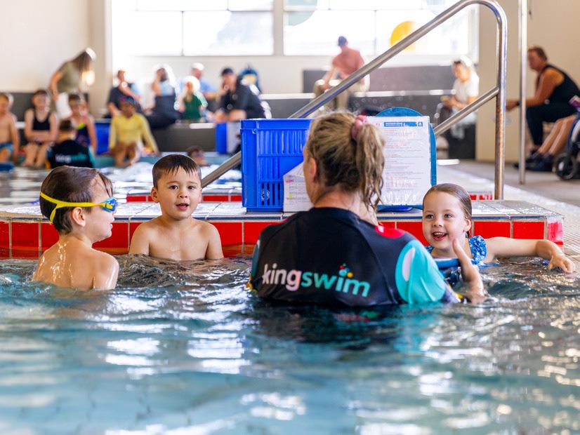 Kingswim teacher in the pool talking to children learning to swim