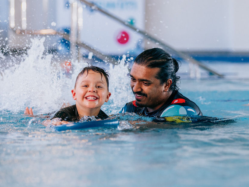 Kingswim swim teacher helping a child learn kicking technique in the pool