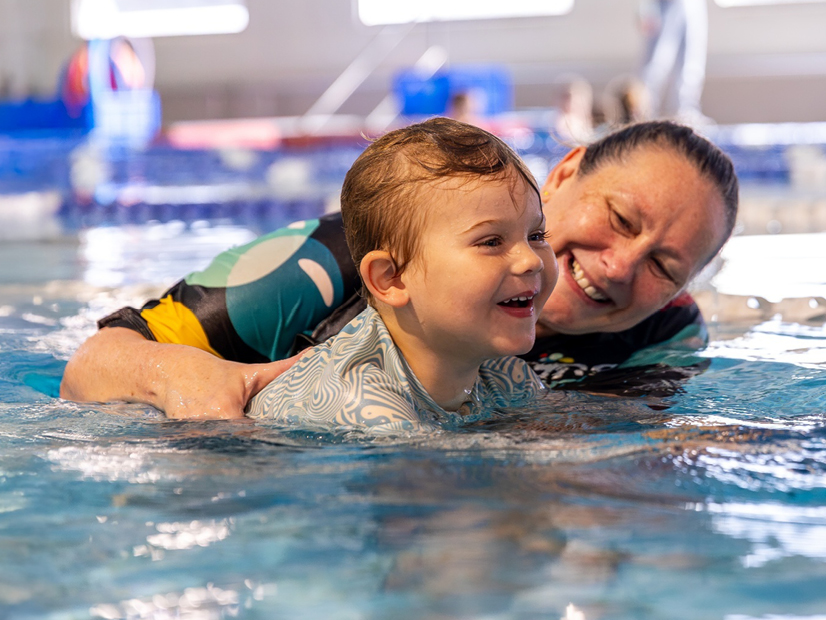 Kingswim teacher helping a toddler to swim on their front